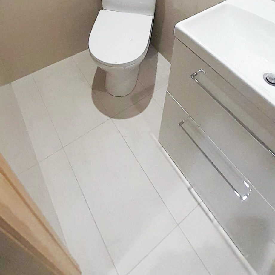 Newly finished tiled toilet floor, toilet unit and basin.